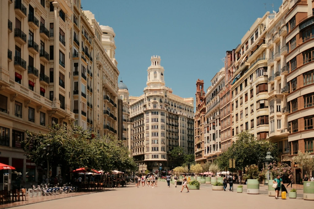 A group of people walking down a street next to tall buildings